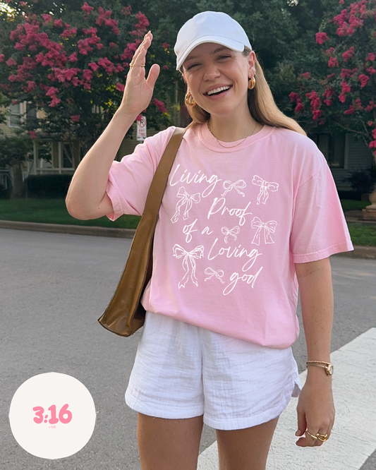 Living Proof of a Loving God – Pink Bow Script Tee